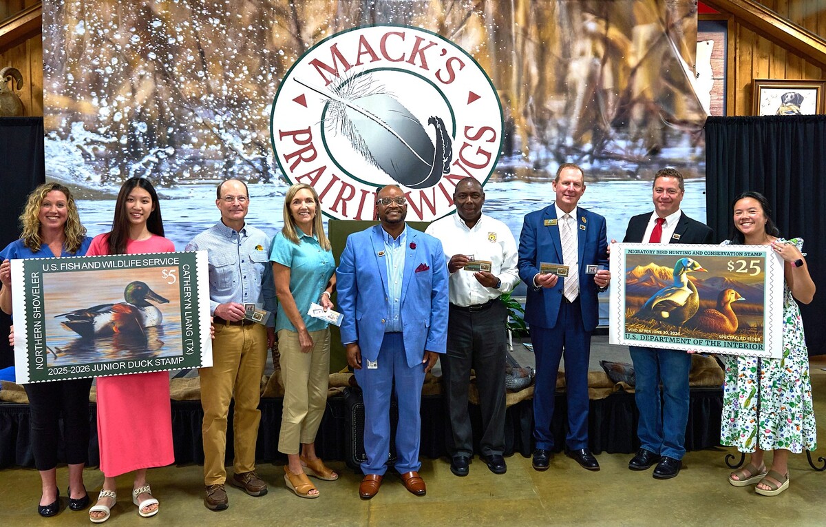 The Service hosted a special event at Mack's Prairie Wings in Stuttgart, Arkansas to celebrate the new Duck Stamps. The 2025-2026 Federal and Junior Duck Stamps are now on sale and can be purchased in select post offices, outdoor stores, and refuges or online. Left to Right: Valerie Fellows, Federal Duck Stamp Office, U.S. Fish and Wildlife Service; Catheryn Liang, Junior Duck Stamp Artist; Bob Ziehmer, Senior Director for Conservation, Bass Pro Shops; Dr. Karen Waldrop, Chief Conservation Officer, Ducks Unlimited; Dameon Shelton, Stuttgart Acting Postmaster, U.S. Postal Service; Jerome Ford, Assistant Director for the U.S. Fish and Wildlife Service Migratory Bird Program;  Doug Schoenrock, Director of Arkansas Game and Fish Commission; Adam Grimm, Federal Duck Stamp Artist; Jen Wright, Federal Duck Stamp Office, U.S. Fish and Wildlife Service 